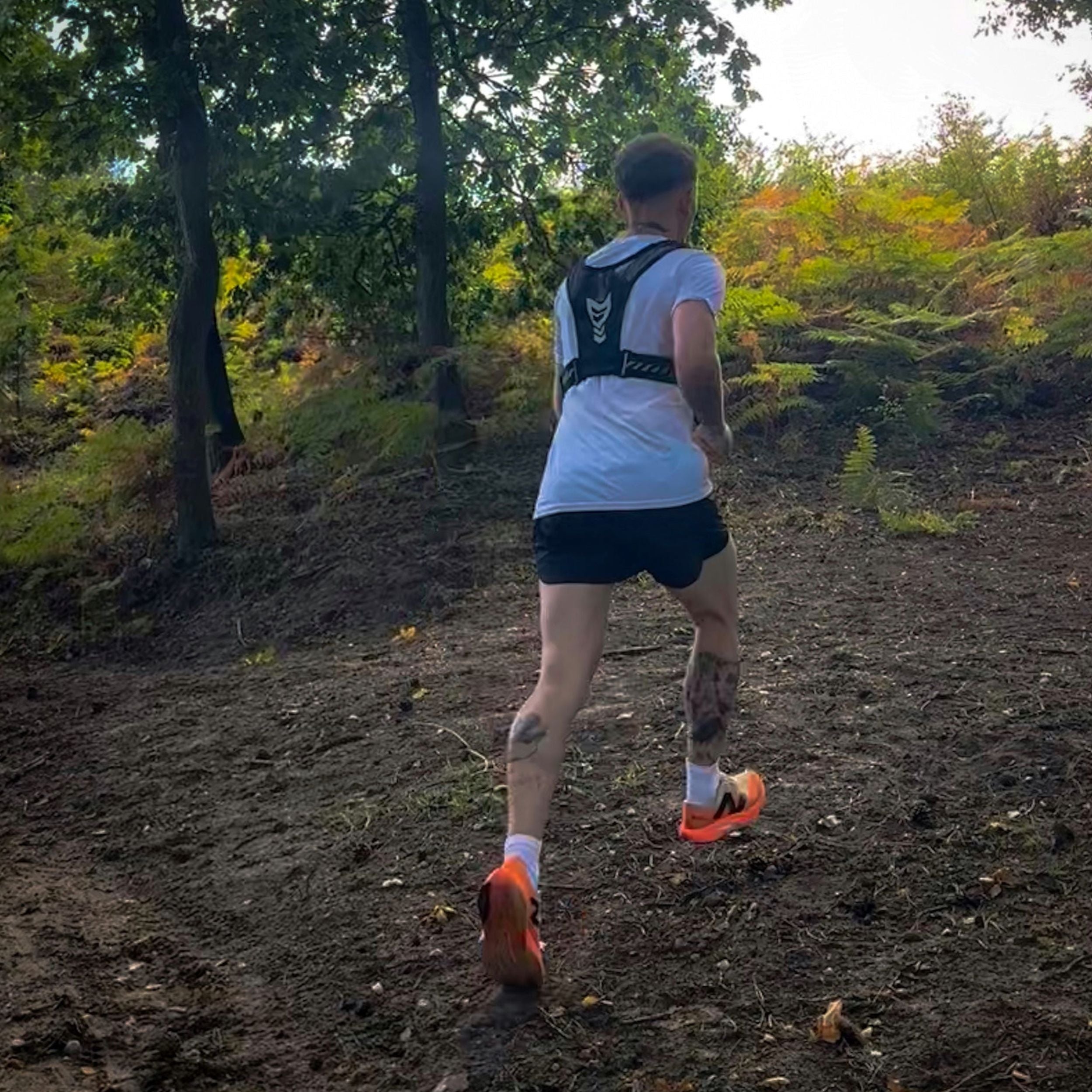 Person running on a dirt trail in a forest wearing black AeroShorts lightweight athletic shorts for running and active wear.