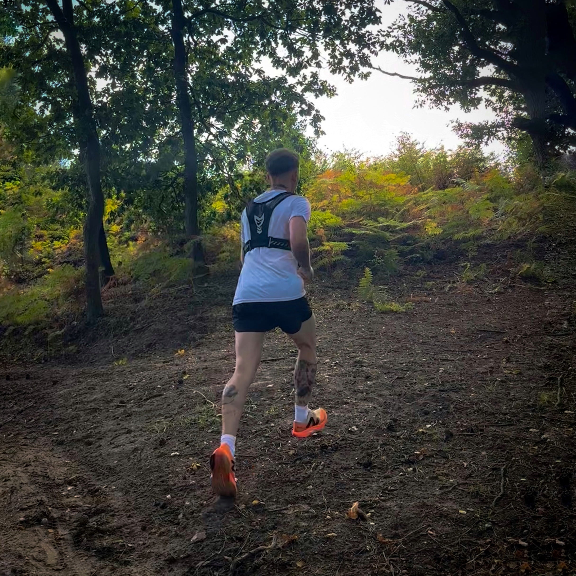 Person running on a dirt trail in a forest wearing black AeroShorts lightweight athletic shorts for running and active wear.