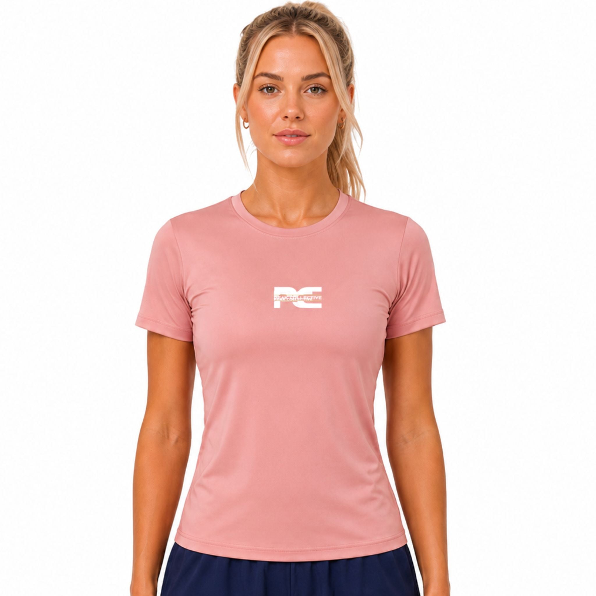 Woman wearing dusky pink AuraTee athletic performance shirt with logo on white background – lightweight women’s running top for gym workouts, training, jogging, and everyday activewear