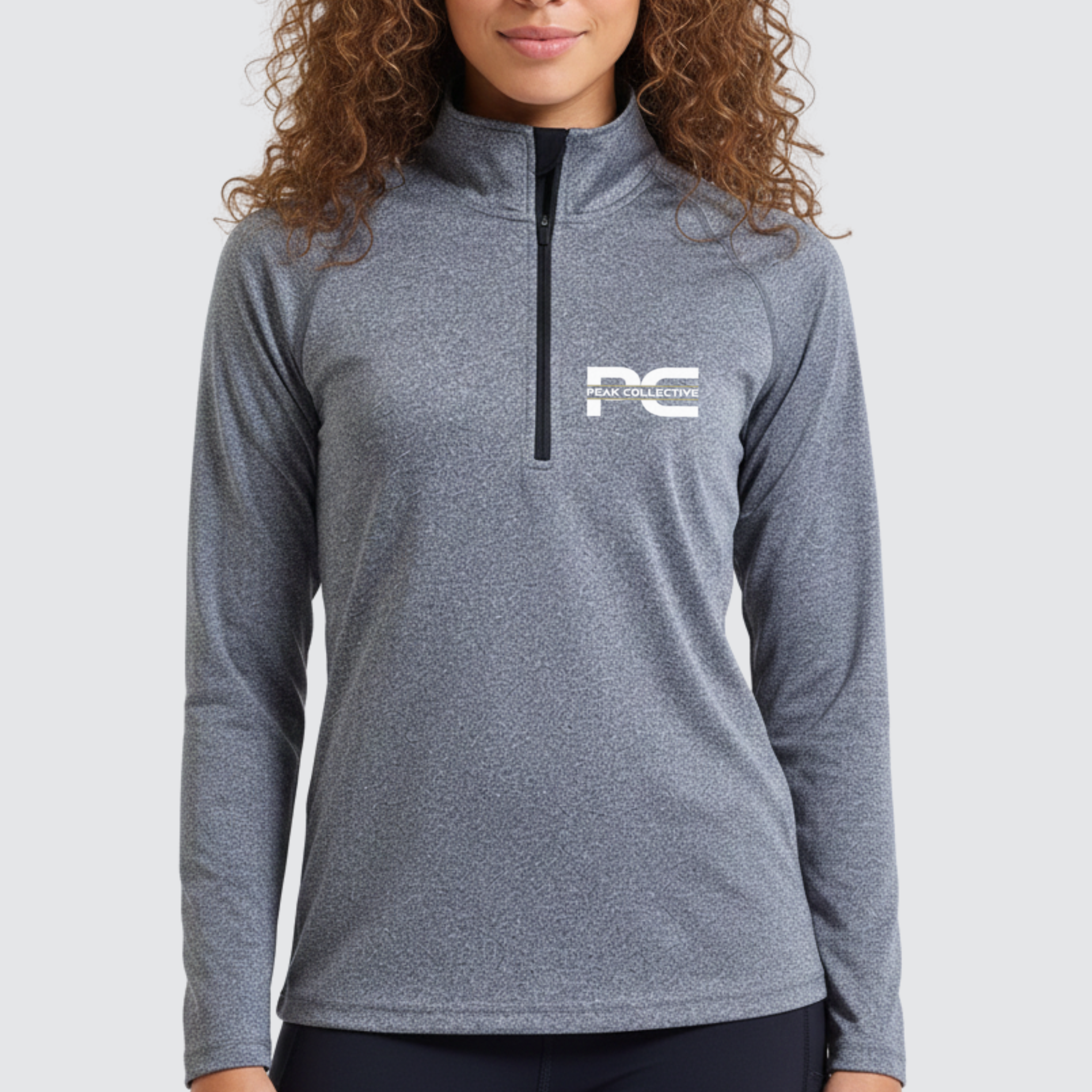 Woman wearing AuraZip 1/4 long sleeve performance top in grey with a visible logo on a light grey background, designed for running, training, and active wear.
