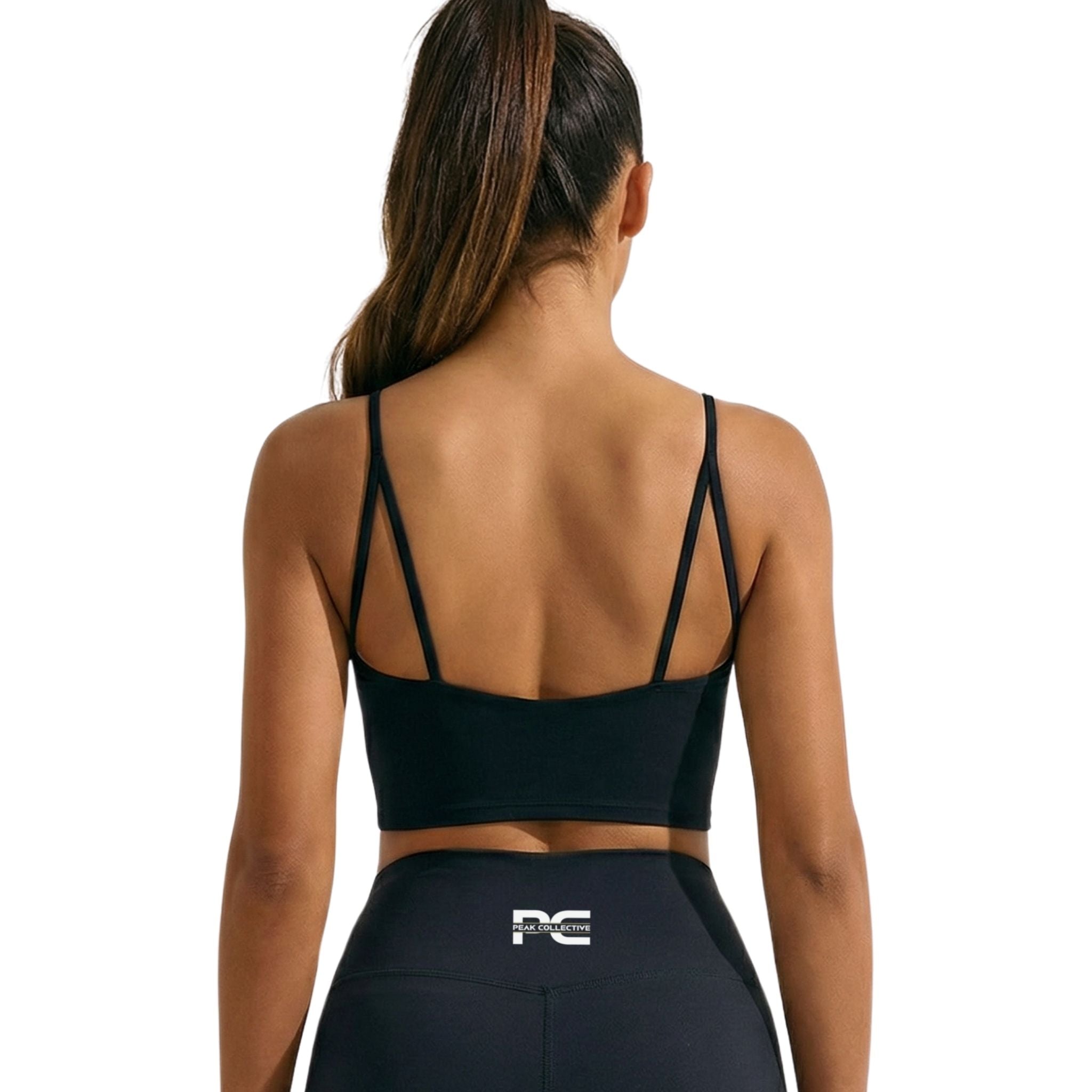 Back view of a woman wearing the black LumaCrop women’s performance crop top with matching AuraShorts, featuring the Peak Collective logo on the AuraShorts a clean white background, designed for running, gym training, and activewear use