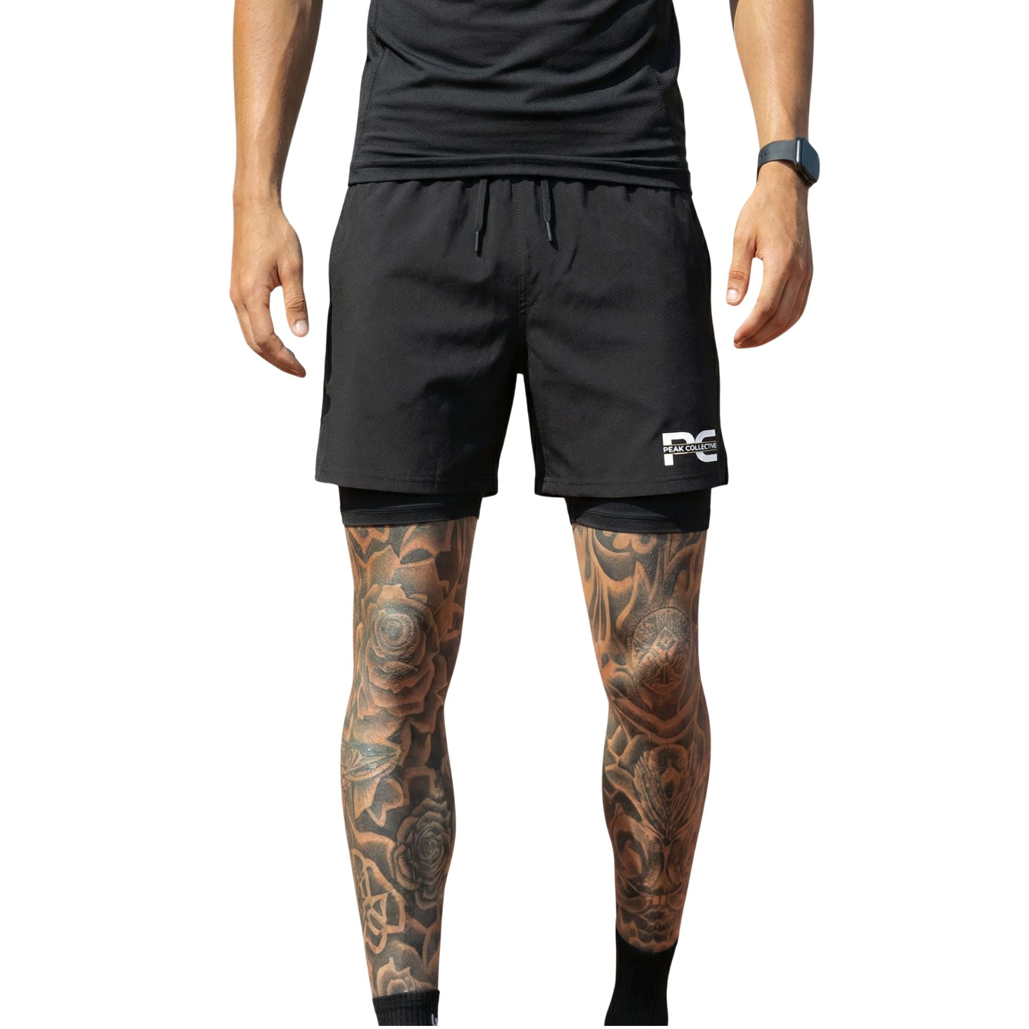 Person wearing StrideShorts men’s black double-layer sports shorts with four-way stretch, integrated undershorts, and zip pockets, ideal for running, gym workouts, and training, on a light grey background.