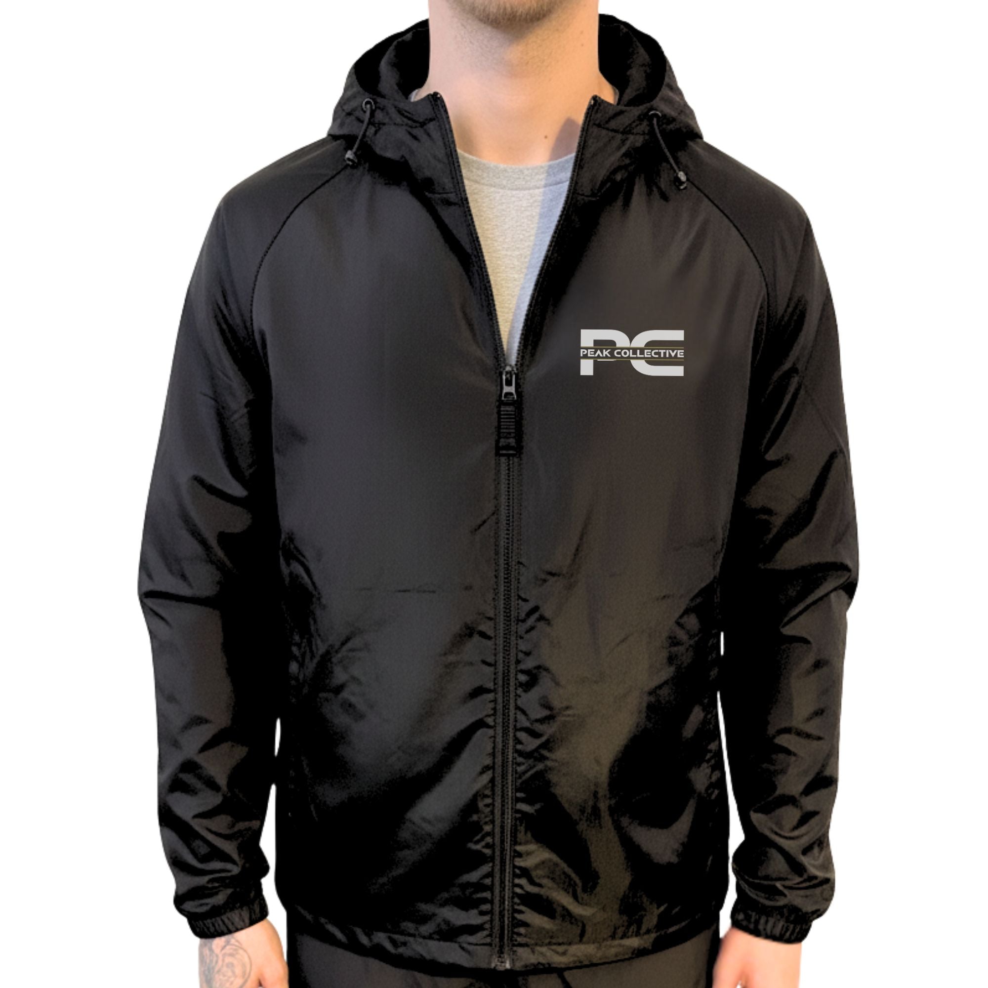 Model wearing AerisShell lightweight performance windbreaker jacket in black with a visible brand logo on a grey background, designed for running, training, and outdoor activity.