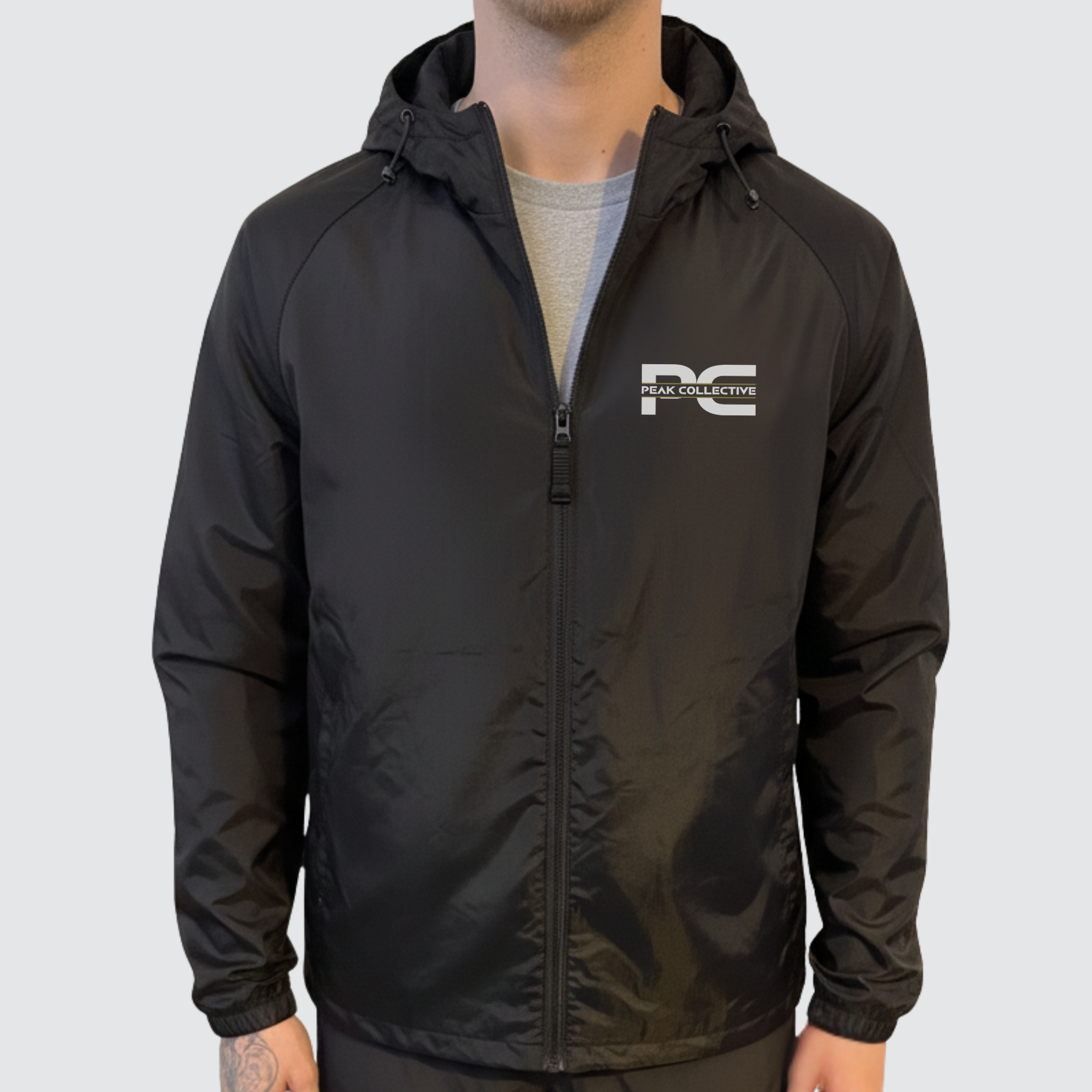 Model wearing AerisShell lightweight performance windbreaker jacket in black with a visible brand logo on a grey background, designed for running, training, and outdoor activity.