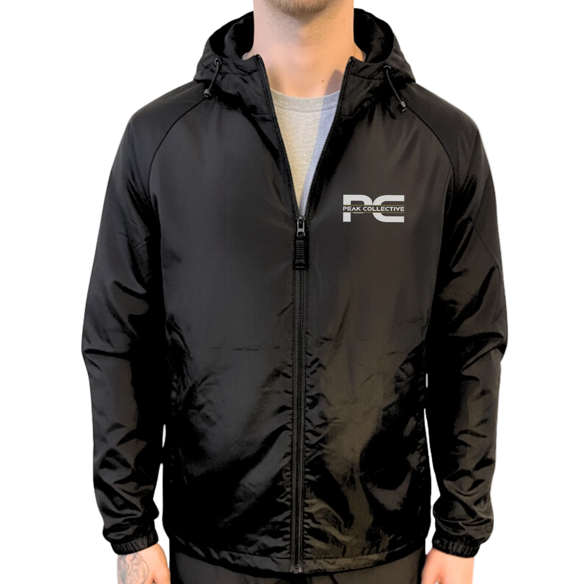 Model wearing AerisShell lightweight performance windbreaker jacket in black with a visible brand logo on a grey background, designed for running, training, and outdoor activity.