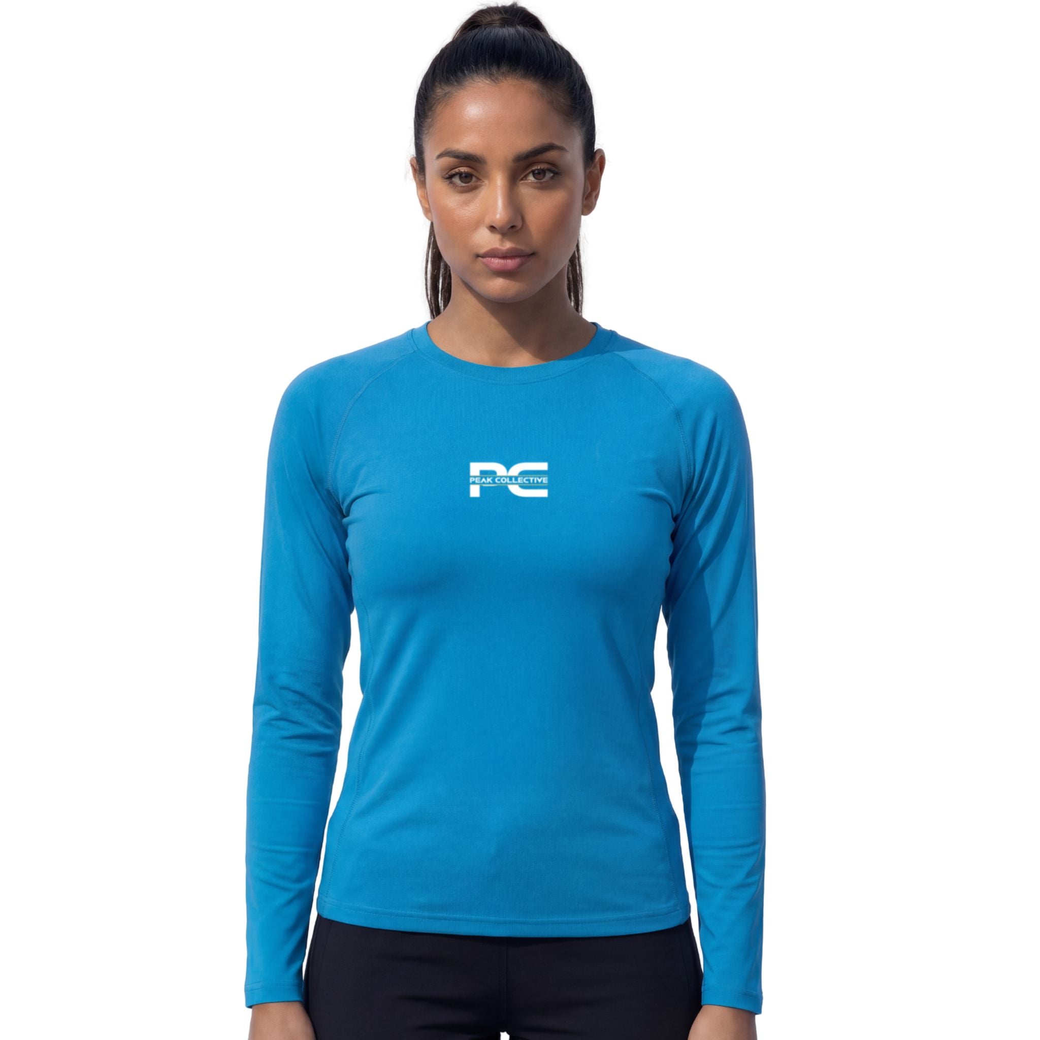 Female model wearing AuraSleeve sapphire long-sleeve performance top with visible Peak Collective logo on white background – lightweight moisture-wicking women’s running shirt for training, running, jogging, gym workouts, and active performance wear