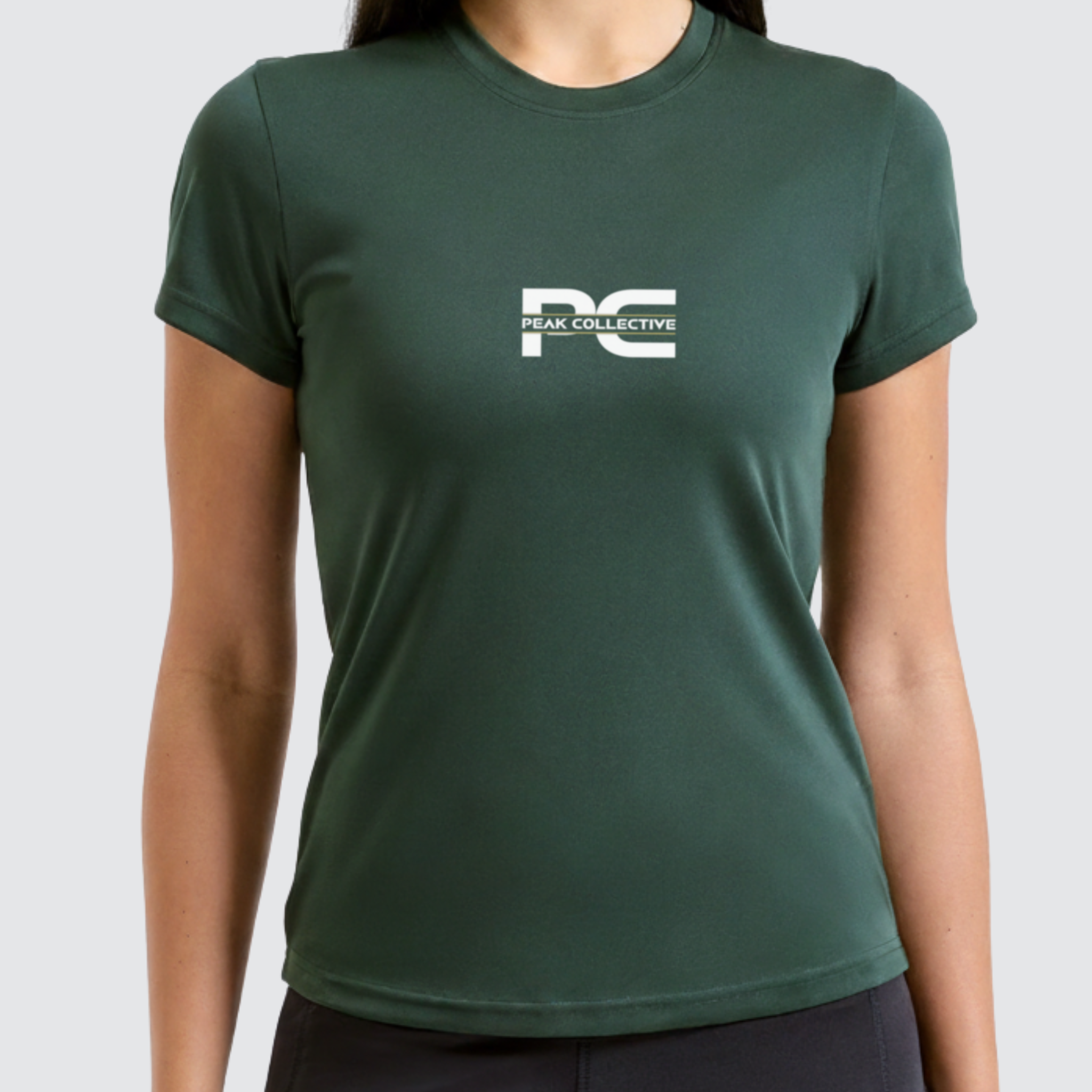 Person wearing AuraTee green t-shirt with Peak Collective logo on a white background, designed for training, running workouts, and everyday active wear.