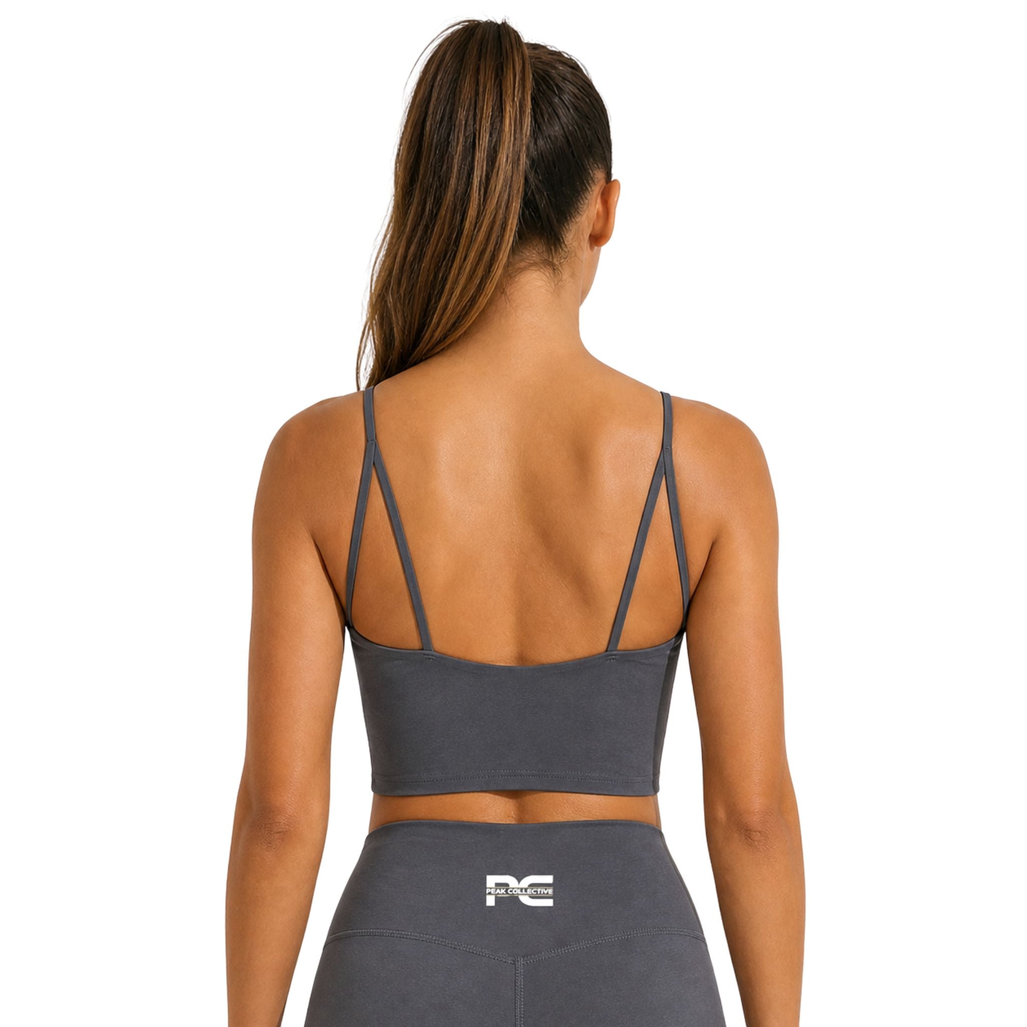 Back view of woman wearing grey LumaCrop sports bra with logo on white background – supportive women’s performance crop top for running, gym workouts, yoga, training sessions, and everyday activewear
