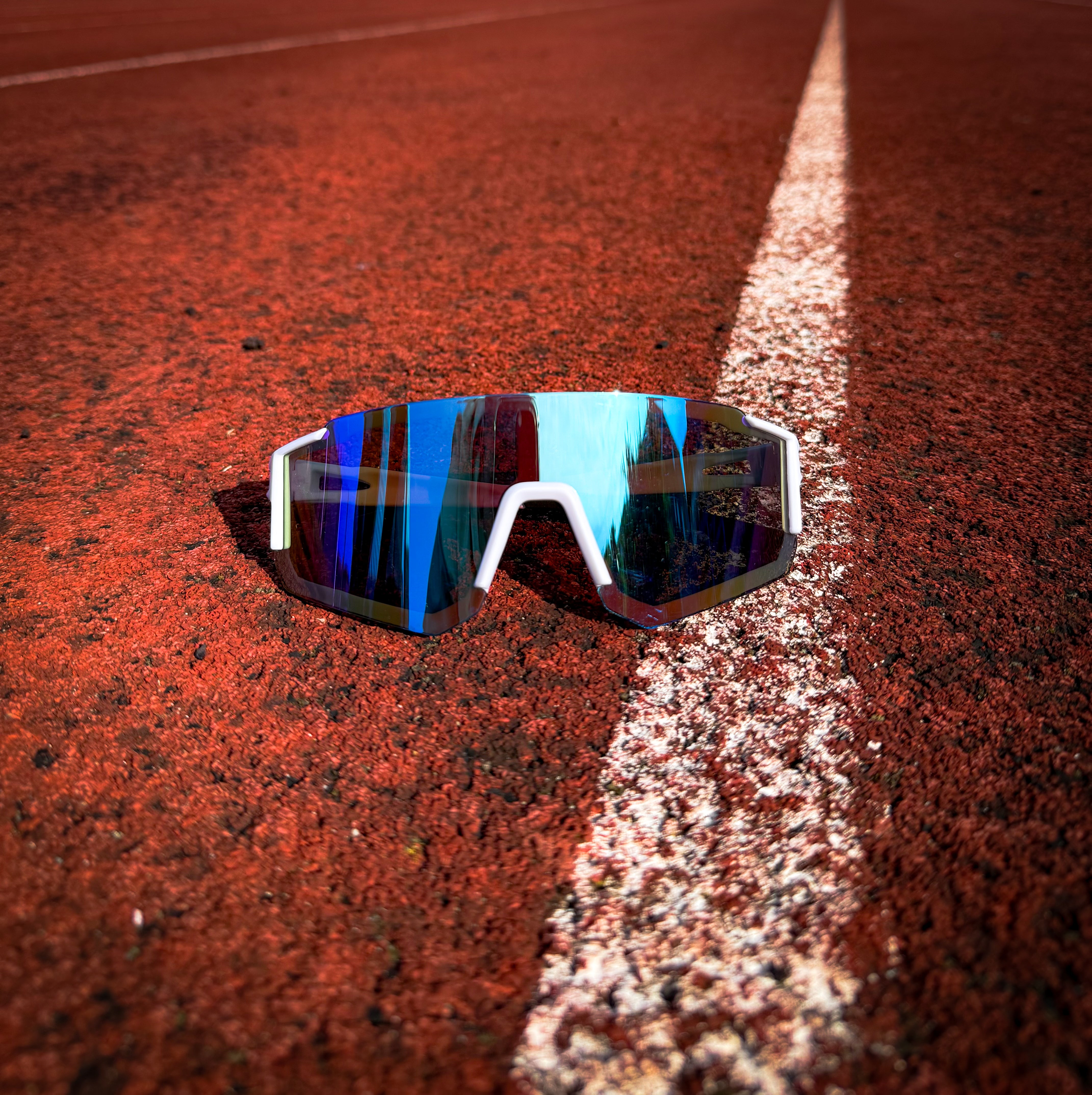 Front view of Blue Fade StormLens performance sunglasses on a red running track, designed for running, training, and outdoor fitness activities.